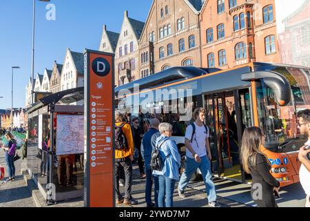 Fermata dell'autobus nel quartiere Bryggen del centro di Bergen con i passeggeri che salgono e scendono sull'autobus a un piano Foto Stock