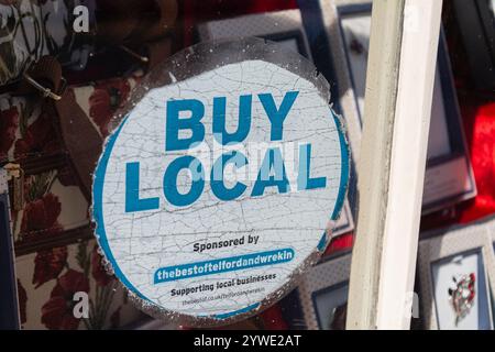 Ironbridge, Shropshire, Regno Unito, 22-06-2018. Un adesivo "acquista locale" nella vetrina di un negozio di articoli da regalo locale. Foto Stock