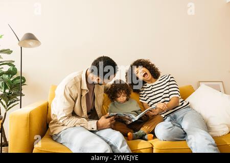 Una famiglia allegra ama il tempo libero leggendo un libro insieme su un divano colorato. La madre del bambino sta facendo delle lamentele mentre legge una storia. Foto Stock