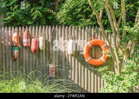 un gruppo di galleggianti e un salvagente appeso su una recinzione Foto Stock