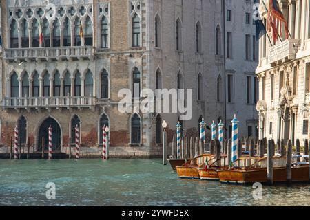 Vecchi motori di lusso in legno ormeggiati sui loro palati sul Canal grande, circondati da edifici storici. Foto Stock