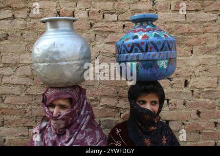 Srinagar, India. 10 dicembre 2024. Le donne di Sonabanjran, una remota zona collinare nel distretto di Pulwama del Kashmir meridionale, stanno affrontando gravi difficoltà a causa delle temperature gelide. Con l'alimentazione dell'acqua di rubinetto interrotta dal congelamento delle linee di alimentazione, i residenti sono stati costretti a raccogliere l'acqua potabile da un flusso congelato. (Foto di Nisar UL Haq Allaie/Pacific Press) credito: Pacific Press Media Production Corp./Alamy Live News Foto Stock