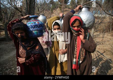 Srinagar, Jammu e Kashmir, India. 10 dicembre 2024. Le donne di Sonabanjran, una remota zona collinare nel distretto di Pulwama del Kashmir meridionale, stanno affrontando gravi difficoltà a causa delle temperature gelide. Con l'alimentazione dell'acqua di rubinetto interrotta dal congelamento delle linee di alimentazione, i residenti sono stati costretti a raccogliere l'acqua potabile da un flusso congelato. (Immagine di credito: © Nisar UL Haq Allaie/Pacific Press via ZUMA Press Wire) SOLO PER USO EDITORIALE! Non per USO commerciale! Foto Stock