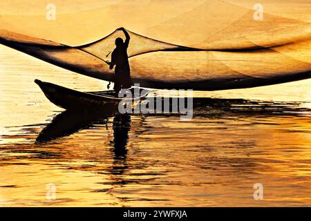 Pescatore che raccoglie pesci dalle sue reti la mattina a Hue, Vietnam Foto Stock