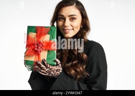 Una giovane donna vivace presenta un regalo colorato con entusiasmo e stile Foto Stock