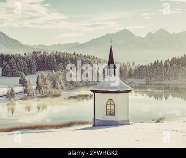 Cappella sul lago nell'Allgaeu innevato vicino a Halblech, di fronte a un paesaggio di montagna impressionante, Baviera, Germania, Europa Foto Stock