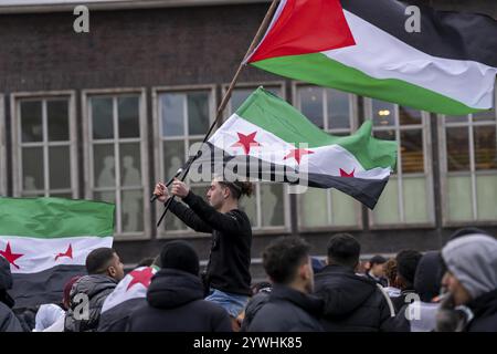 La gente celebra la fine del regime di Assad dopo il cambio di potere in Siria in un raduno sulla piazza di fronte alla stazione ferroviaria principale di Duisb Foto Stock