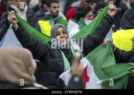 La donna siriana celebra la fine del regime di Assad dopo il cambio di potere in Siria in un raduno sulla piazza di fronte alla stazione ferroviaria principale di Foto Stock