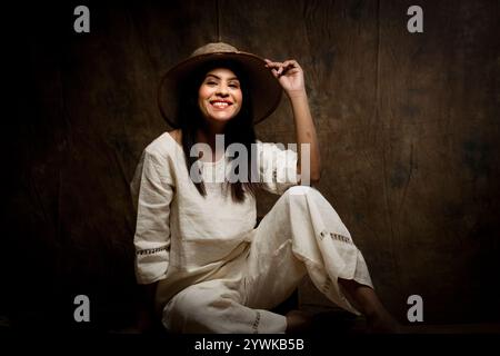 Una splendida modella femminile che sfoggia eleganza in una camicia e pantaloni in lino bianco. Una splendida donna che posa con sicurezza in un outfit tutto bianco Foto Stock