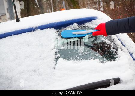 Mano di donna con spazzola e rimuovere la neve dalla vettura e dal parabrezza. Problemi invernali nel trasporto Foto Stock