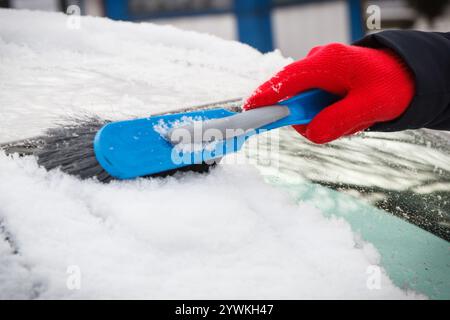 Mano di donna con spazzola e rimuovere la neve dalla vettura e dal parabrezza. Problemi invernali nel trasporto Foto Stock