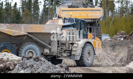 I camion ribaltabili viaggiano su una strada che conduce a un cantiere edile Foto Stock