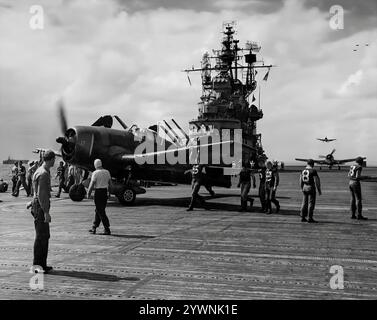 Il Grumman F6F Hellcat su un ponte di volo portaerei era un aereo da caccia statunitense della seconda guerra mondiale, progettato per sostituire il precedente F4F Wildcat e contrastare il giapponese Mitsubishi A6M Zero. L'aereo ha fatto il suo debutto in combattimento nel settembre 1943 e successivamente si è affermato come un robusto caccia portaerei ben progettato e divenne il caccia dominante della United States Navy nella seconda metà della guerra del Pacifico. In totale, 12.275 furono costruiti in poco più di due anni e alla Hellcats fu attribuito il merito di aver distrutto un totale di 5.223 aerei nemici durante il servizio. Foto Stock