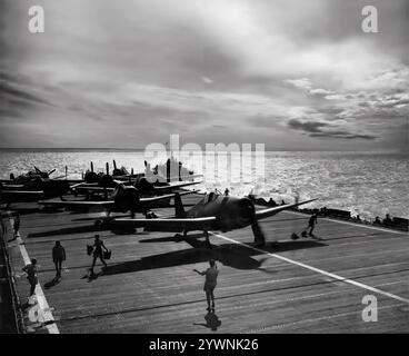 Fleet Air Arm Grumman F6F Hellcats si prepara al decollo sul ponte di volo della HMS Ameer, una portaerei di scorta americana, trasferita alla Royal Navy a metà del 1943. L'aereo da caccia americano basato sulle portaerei della seconda guerra mondiale ha fatto il suo debutto in combattimento nel settembre 1943 e successivamente si è affermato come un caccia da portaerei robusto e ben progettato. Divenne il combattente dominante della Marina degli Stati Uniti nella seconda metà della guerra del Pacifico. In totale, 12.275 furono costruiti in poco più di due anni e alla Hellcats fu attribuito il merito di aver distrutto un totale di 5.223 aerei nemici durante il servizio. Foto Stock