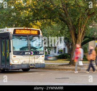 New Orleans, LOUISIANA, USA - 10 gennaio 2024: L'autobus si ferma all'incrocio di S. Carrollton Avenue e Oak Street e la gente attraversa rapidamente la strada in movimento sfocato Foto Stock