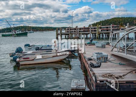 Piccole imbarcazioni a base di aragosta presso un molo del New England: Le casse di aragosta si trovano in acqua e su un molo galleggiante dove si legano piccole barche da pesca. Foto Stock