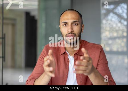 Uomo vestito in modo informale, usando gesti spiegati durante la conversazione, trasmettendo comunicazione e interazione in un contesto professionale o personale. Foto Stock