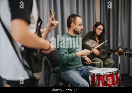 Tre musicisti che praticano insieme a chitarra, basso e batteria in uno studio Foto Stock
