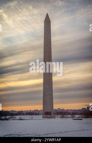 Una vista grandangolare del Monumento a Washington durante un pittoresco tramonto invernale, circondato dalla neve e un tranquillo bagliore serale sul National Mall. Foto Stock