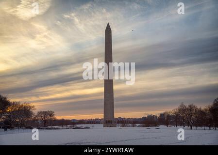 Il monumento a Washington sul National Mall di Washington, D.C., si trova sullo sfondo di nuvole morbide e colorate al tramonto e di un paesaggio innevato. Foto Stock