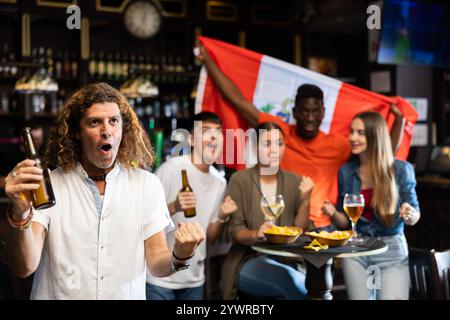 Amici felici che celebrano la vittoria della squadra peruviana nel bar della birra Foto Stock