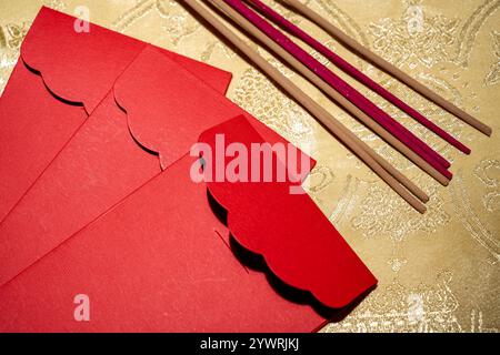 La pila di buste rosse o angpao con bastoncini di incenso su sfondo giallo. Mockup, modello vuoto, spazio di copia. Decorazione per Lunar o Chin Foto Stock