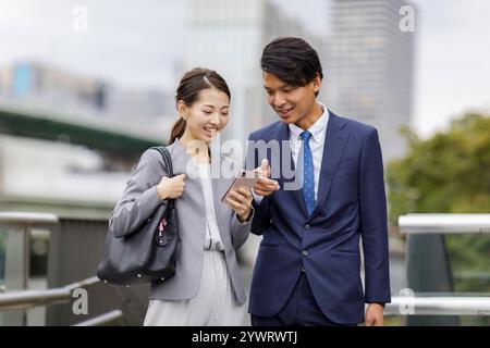 Uomini e donne d'affari che guardano gli smartphone Foto Stock