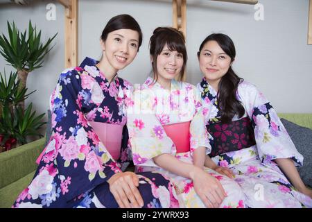 Tre giovani donne che si rilassano all'interno di un ryokan nello yukata Foto Stock