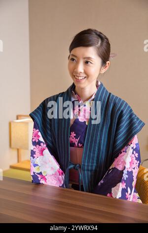 Giovane donna che si rilassa all'interno di un ryokan in uno yukata Foto Stock