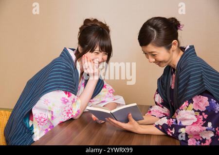 Due giovani donne che si rilassano all'interno di un ryokan nello yukata Foto Stock