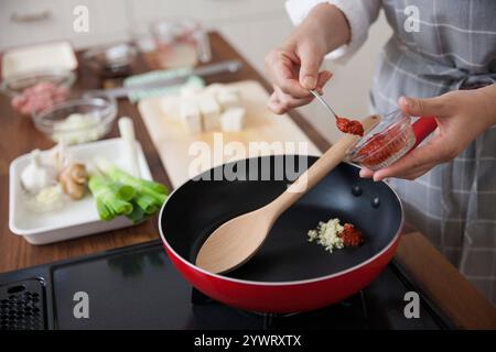 Donna che mette l'aglio e i germogli di soia in una padella Foto Stock