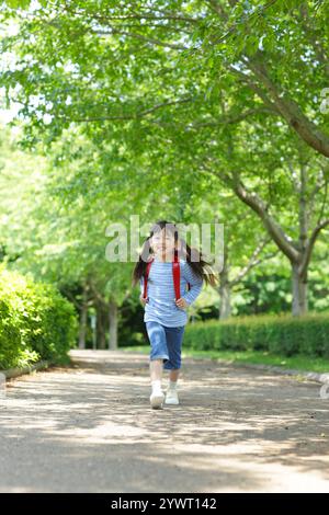 Ragazza che porta una borsa sulla schiena che cammina lungo un percorso verde fresco Foto Stock