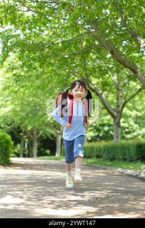 Ragazza che porta una borsa sulla schiena che cammina lungo un percorso verde fresco Foto Stock