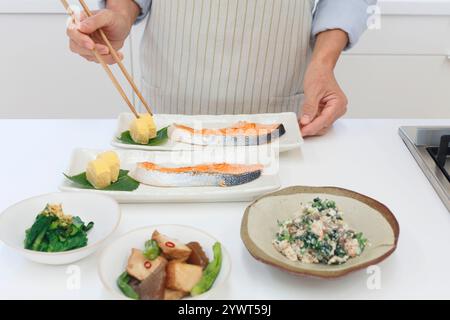 Cibo giapponese preparato da un uomo di mezza età che indossa un grembiule Foto Stock