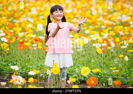 Ragazza che gioca nel campo del papavero Foto Stock