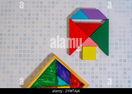 Un colorato puzzle Tangram che forma una figura con il suo contenitore su un tavolo di legno. Foto Stock