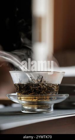 Provate il processo rilassante di cottura a vapore dell'infusione di tè in una teiera di vetro finemente lavorata Foto Stock