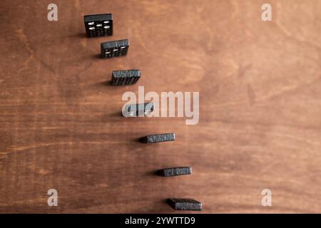 set di piastrelle in domino bianco e nero in ordine su tavolo in legno - effetto domino concetto - Foto Stock