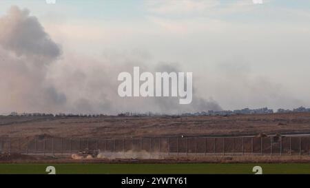 CONFINE con GAZA, ISRAELE - 10 DICEMBRE: Un carro armato israeliano rotola lungo il confine con Gaza come un massiccio flusso di fumo dopo il bombardamento israeliano nella parte settentrionale di Gaza, nel mezzo delle continue battaglie tra Israele e il gruppo militante Hamas il 10 dicembre 2024 al confine con Gaza, Israele. Foto Stock