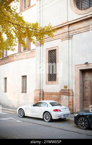Cremona, Italia - 27 novembre 2024 White bmw z4 e89 sdrive28i parcheggio stradale vicino ad un vecchio edificio con foglie d'autunno gialle, trasporti e lux Foto Stock