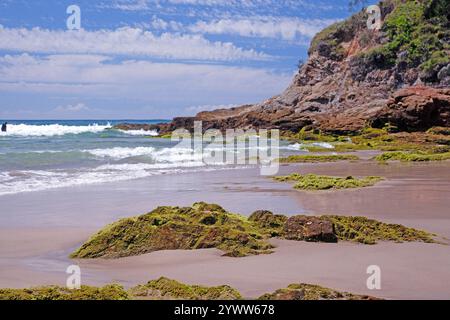 Costa rocciosa sulla Golden Coast, Australia, con rocce coperte di muschio e onde oceaniche che si infrangono durante il giorno Foto Stock