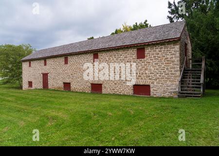 Un fienile in pietra a due piani con un tetto di scandole grigie, persiane rosse e una scala esterna in legno si trova al Hampton National Historic Site, nel Maryland. Foto Stock