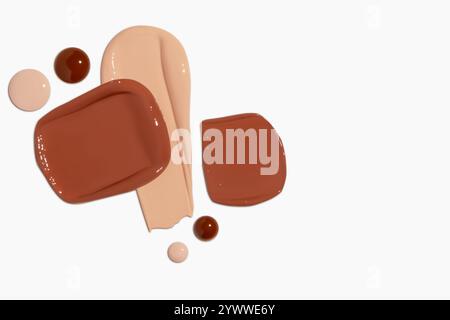 Composizione di strisci e gocce di fondamento liquido in varie tonalità, tra cui toni chiari e scuri, isolati su uno sfondo chiaro. Foto Stock