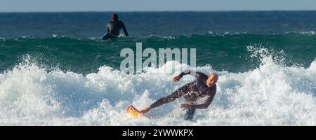 Un'immagine panoramica di un surfista maschio maturo che spazza via su un'onda al Fistral di Newquay in Cornovaglia nel Regno Unito in Europa Foto Stock