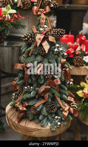 Albero di Natale in miniatura adornato con coni, archi, palle e bastoncini di cannella Foto Stock