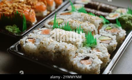 Deliziosi panini di sushi in vassoi con vari ingredienti come salmone, avocado e alghe marine, presentati splendidamente per una deliziosa esperienza culinaria Foto Stock