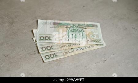 Banconote polacche da 100 zloty disposte su una superficie di cemento che mostra la valuta polacca in un ambiente semplice e autentico. Foto Stock