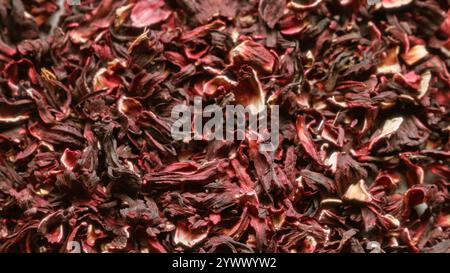 Petali di ibisco essiccati che creano un colorato sfondo testurizzato con ricche sfumature rosse e dettagli complessi Foto Stock