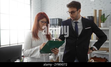 I dirigenti ispanici di uomini e donne collaborano in un ufficio moderno, esaminando documenti e discutendo strategie aziendali in ambienti chiusi. Foto Stock