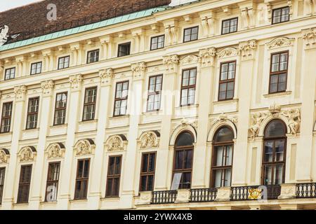 Vienna, Austria - 12 maggio 2019: Finestre di un bellissimo palazzo con sculture sopra la, foto ravvicinata. Antica architettura di edifici residenziali Foto Stock